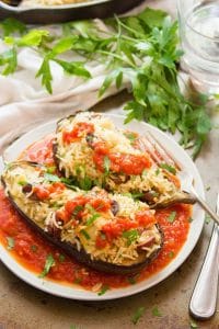 Mediterranean Stuffed Eggplant on a Plate with Fork and a Bunch of Parsley in the Background