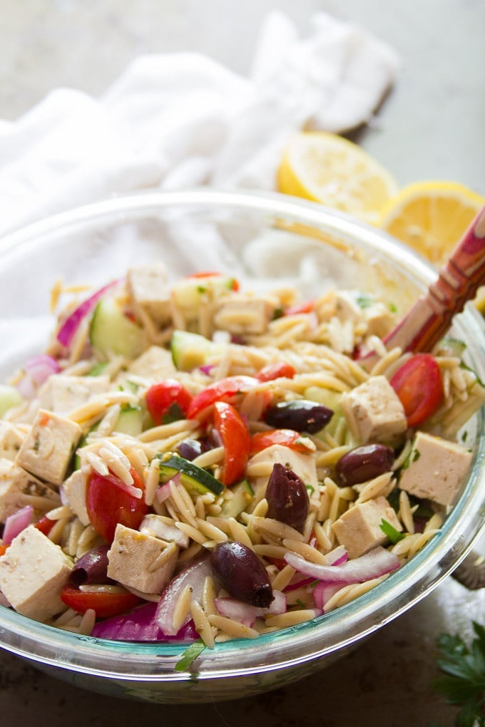 Serving Bowl Filled with Vegan Greek Orzo Salad With Spoon