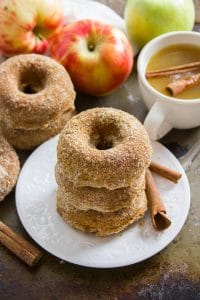 Stack of Vegan Apple Cider Doughnuts on a Plate with Cinnamon Sticks