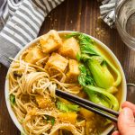 Hand with Chopsticks Grabbing a Bunch of Noodles from a Bowl of Warming Pumpkin Ramen