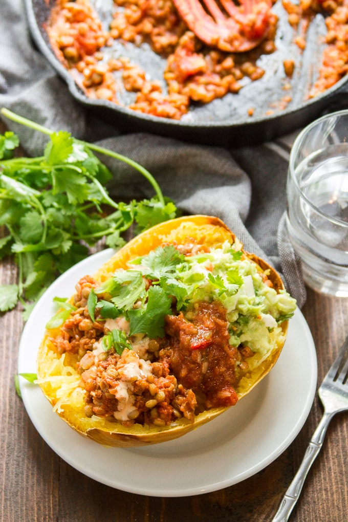 Taco Stuffed Spaghetti Squash on a Plate with Drinking Glass and Skillet in the Background