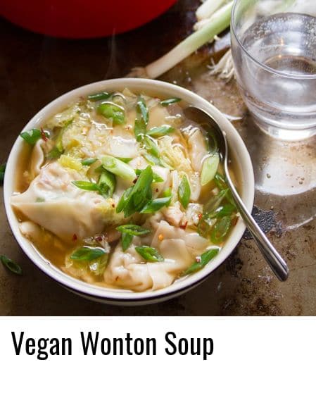 Bowl of Vegan Wonton Soup with Water Glass and Bunch of Scallions in the Background