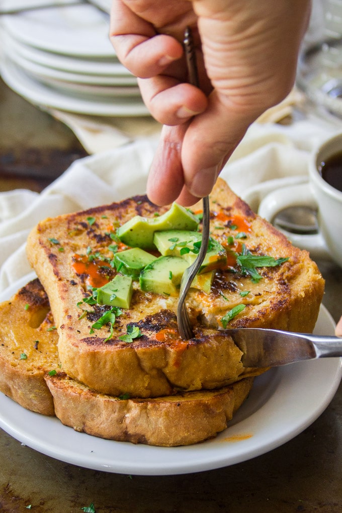 Hands with Fork and Knife Cutting Up Two Pieces of Savory Vegan French Toast on a Plate