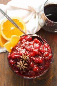 Overhead View of a Bowl of Spiced Wine Cranberry Sauce with Wine Glass and Orange Slices