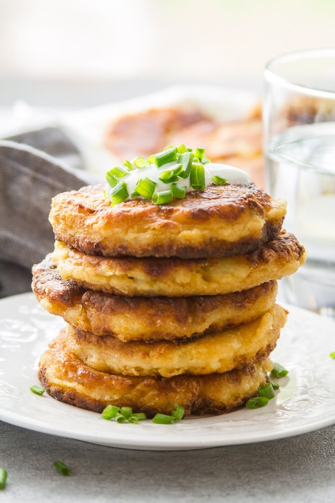 Table Level View of a Stack of Cheesy Vegan Mashed Potato Pancakes Topped with Vegan Yogurt and Chives