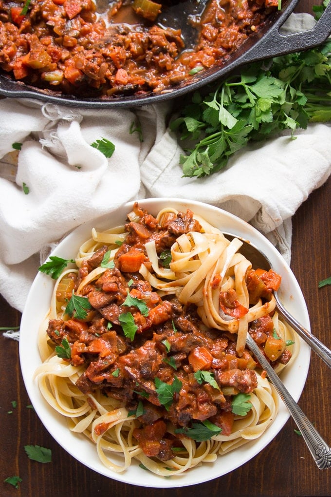 Overhead View of a Bowl of Pasta with Mushroom Bolognese with Fork and Spoon, Skillet and Napkin