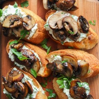 Overhead View of a Wooden Platter of Mushroom Crostini with Herbed Cashew Cheese