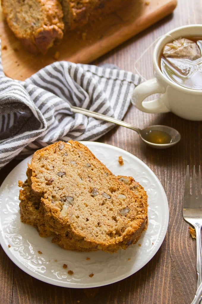Two Slices of Vegan Banana Bread on a Plate with Teacup and Napkin in the Background