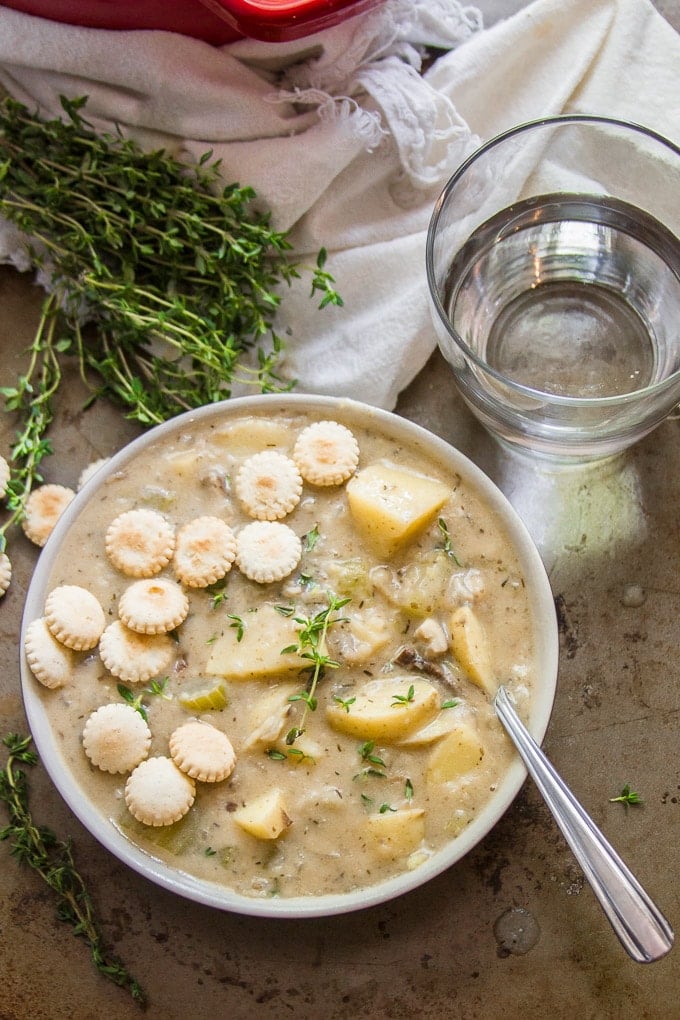 Overhead View of a Bowl of Vegan Clam Chowder with Drinking Glass, Spoon and a Bunch of Thyme