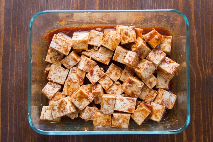Tofu Marinating in a Dish to Make Overhead View of a Plate of Roasted Vegetable Biryani with Baked Tofu