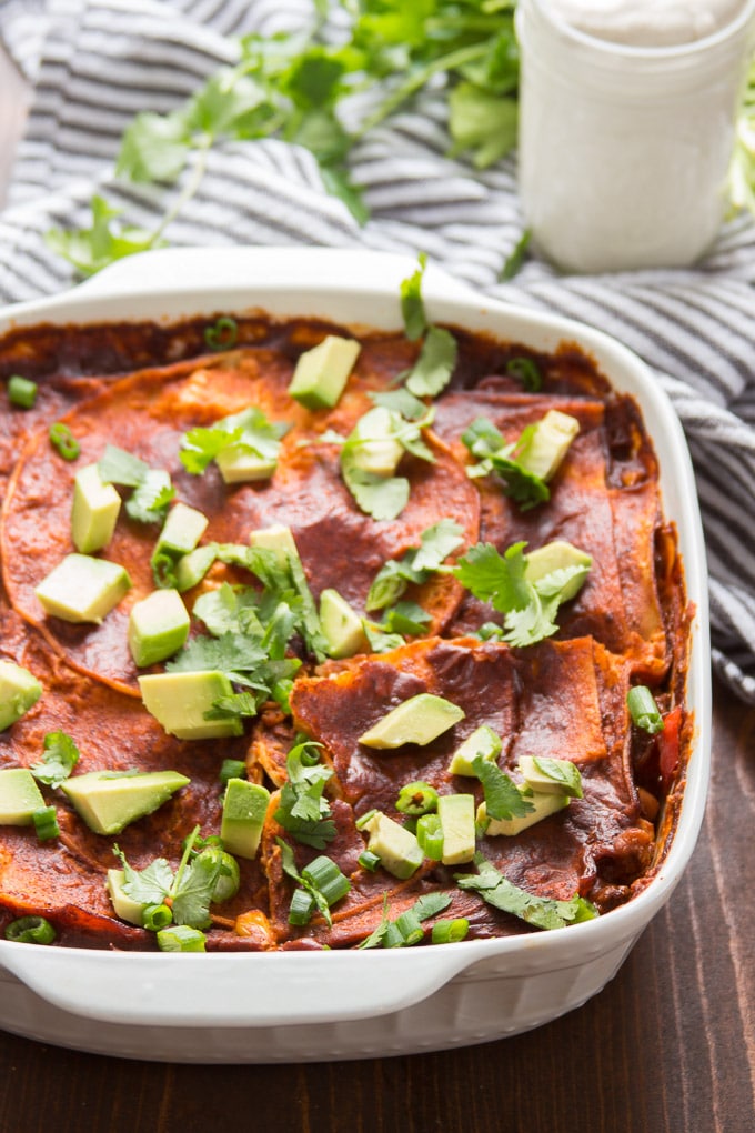 Loaded Enchilada Casserole Topped with Avocado and Cilantro in a Baking Dish
