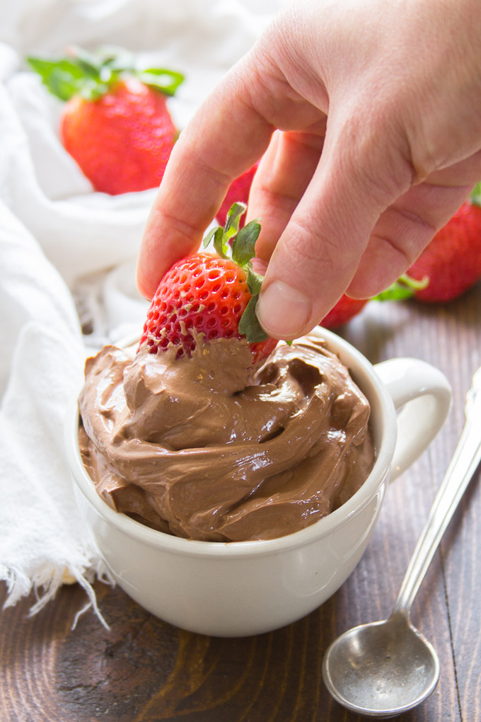 Hand Dipping a Strawberry in a Bowl of Vegan Chocolate Pudding