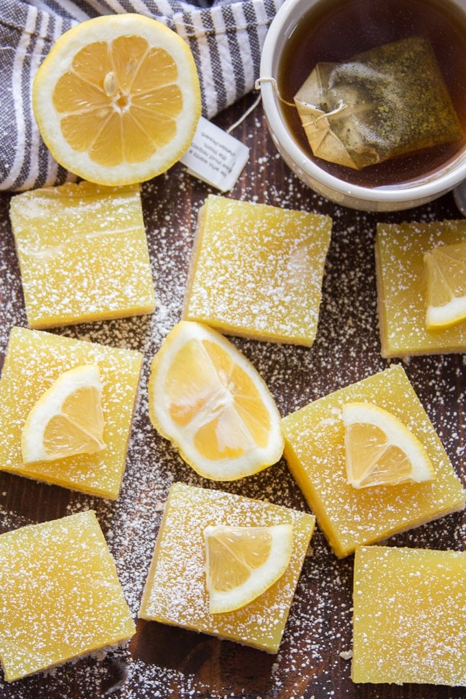 Vegan Lemon Bars Arranged on a Surface with Tea Cup and Lemon Half