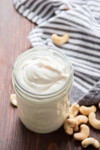 A Jar of Cashew Cream and Raw Cashews Scattered on a Napkin