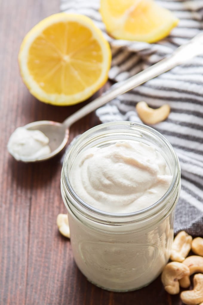Jar of Cashew Cream with Raw Cashews and a Lemon Half in the Background