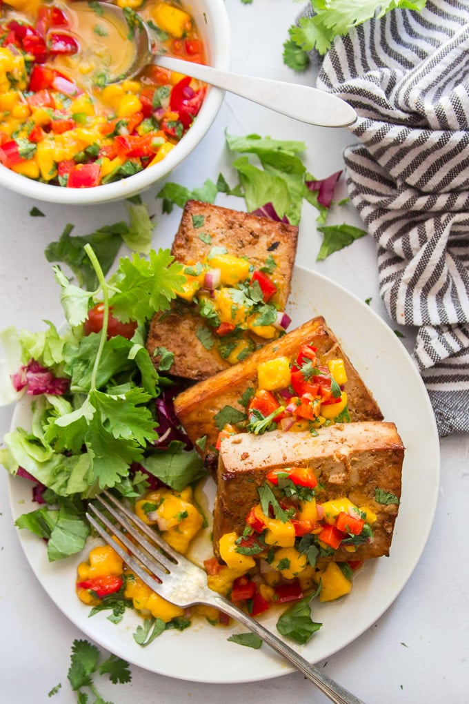 Grilled Tofu, Mango Salsa and Fresh Greens on a Plate with Fork and Striped Napkin