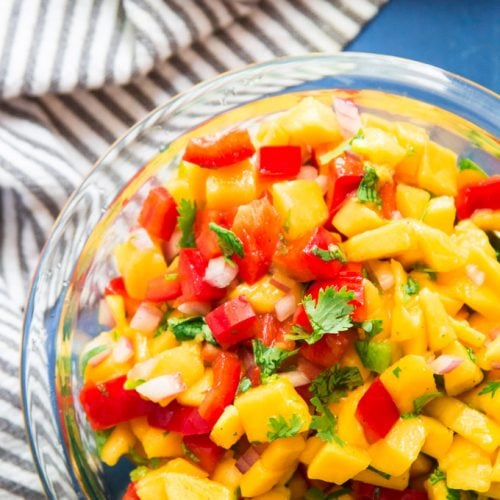 Close Up of a Bowl of Mango Salsa on a Blue Background
