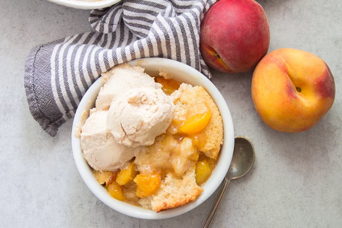 Vegan Peach Cobbler in a Bowl with a Scoop of Ice Cream