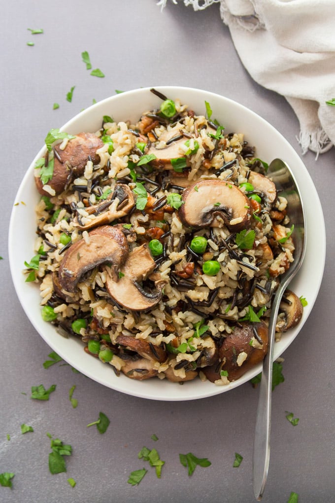 A Bowl of Wild Rice Pilaf with Mushrooms and Pecans with Serving Spoon
