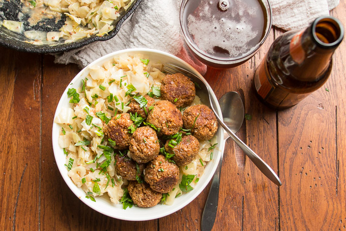 Vegan German Meatballs & Cabbage in a Bowl on a Wooden Table with Fork, Spoon and Glass of Beer