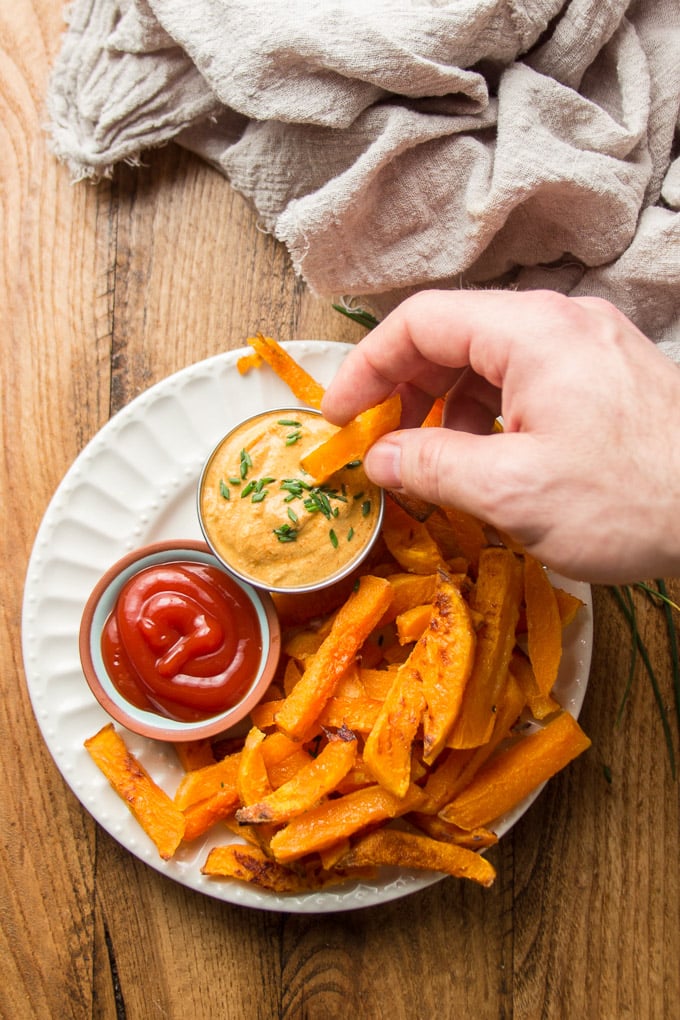 Hand Dipping a Butternut Squash Fry in a Bowl of Aioli