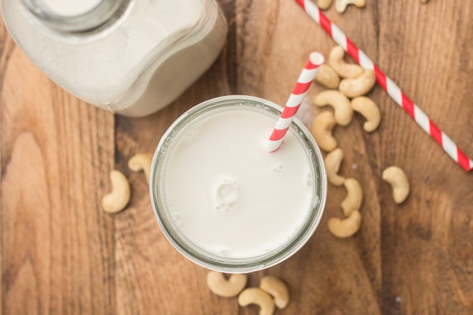 Glass and Bottle of Cashew Milk on a Wooden Table with Cashews