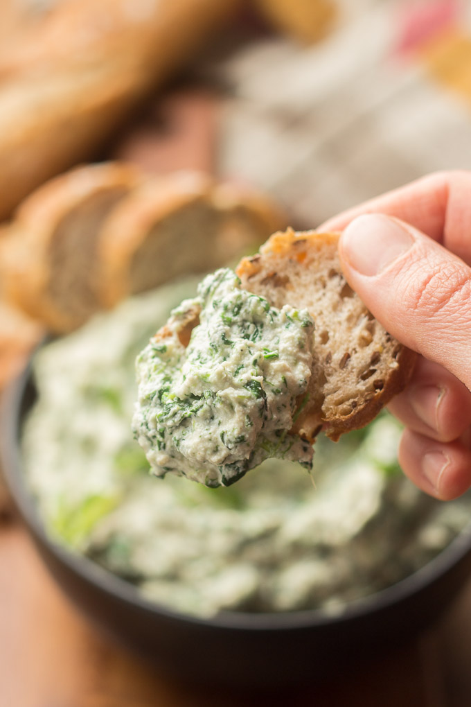Close Up of Hand Holding a Bread Slice Coated with Vegan Spinach Dip