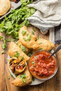 Table Set with a Plate of Vegan Empanadas and Salsa, with One Empanada Cut in Half to Show Filling