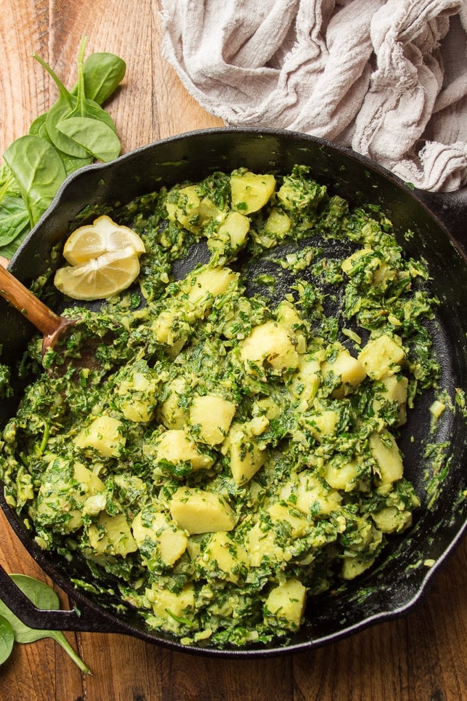 Skillet Filled with Aloo Palak on a Wooden Table