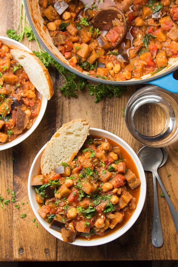 Two Bowls of Eggplant Stew with Bread Slices and Parsley on Top