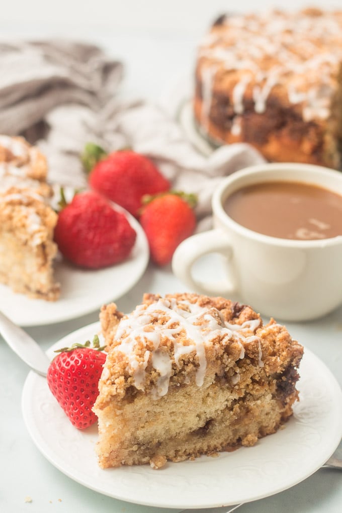 Two Slices of Vegan Coffee Cake on a Table with Coffee and Strawberries