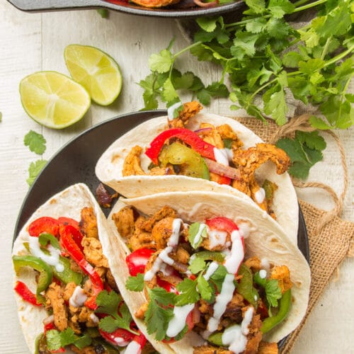 Table Set with a Plate of Vegan Chicken Fajitas, Cast Iron Skillet, and a Bunch of Cilantro