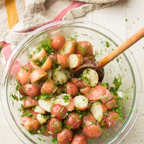 Dijon & Herb Potato Salad in a Glass Bowl with Wooden Spoon