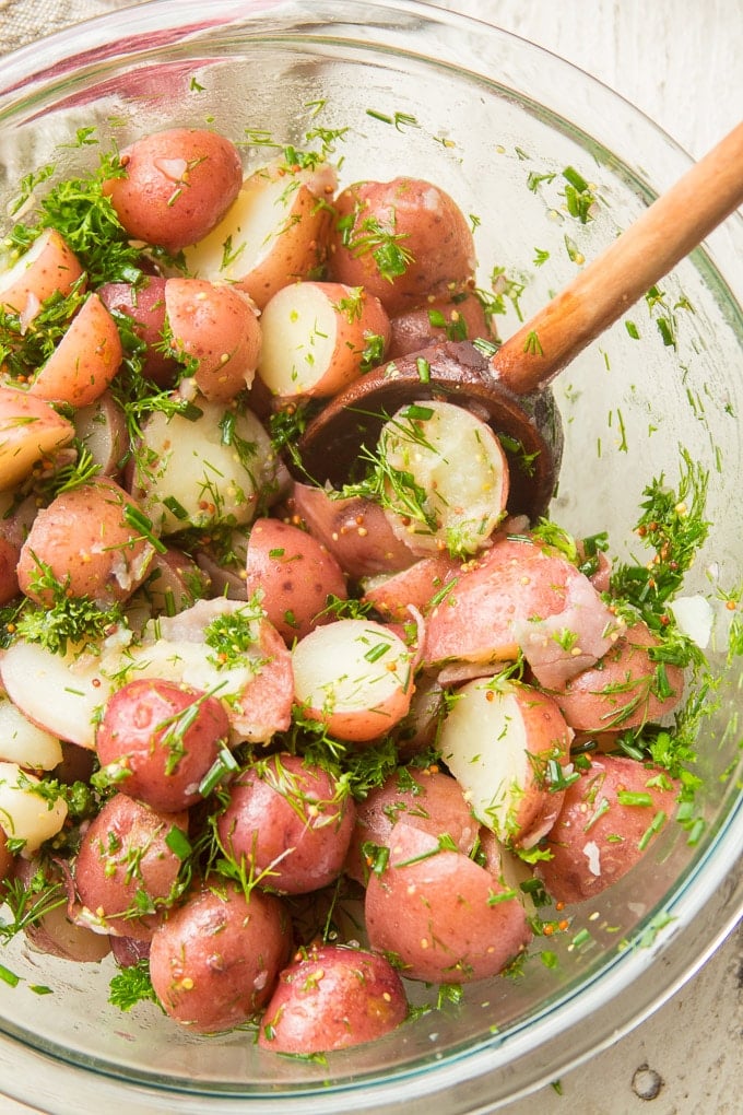 Close Up of Dijon & Herb Potato Salad in a Bowl with Wooden Spoon