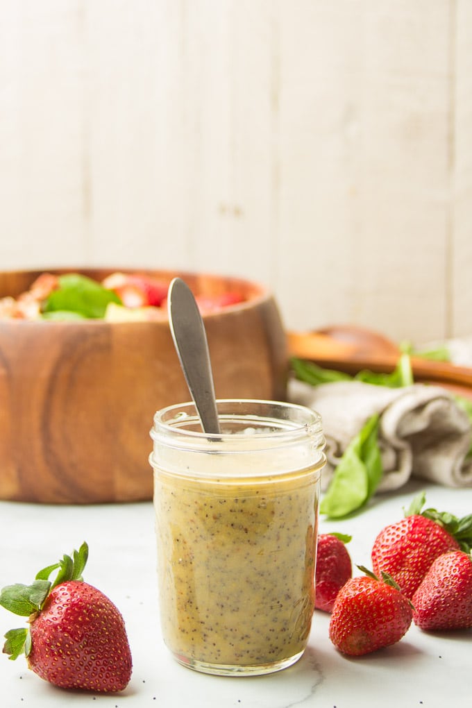 Jar of Poppy Seed Dressing with Salad Bowl and Strawberries in the Background