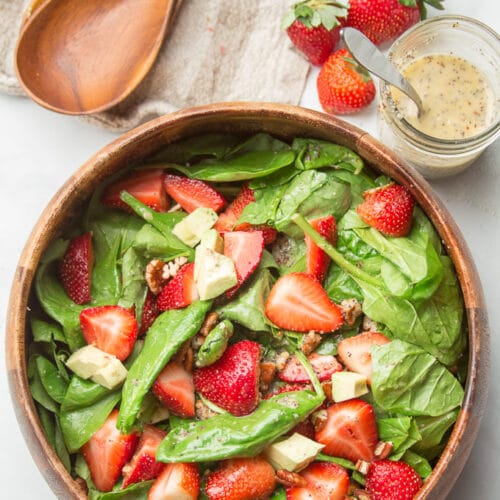 Kitchen Counter Set with a Bowl of Strawberry Spinach Salad, Dressing, Strawberries and Wooden Spoons