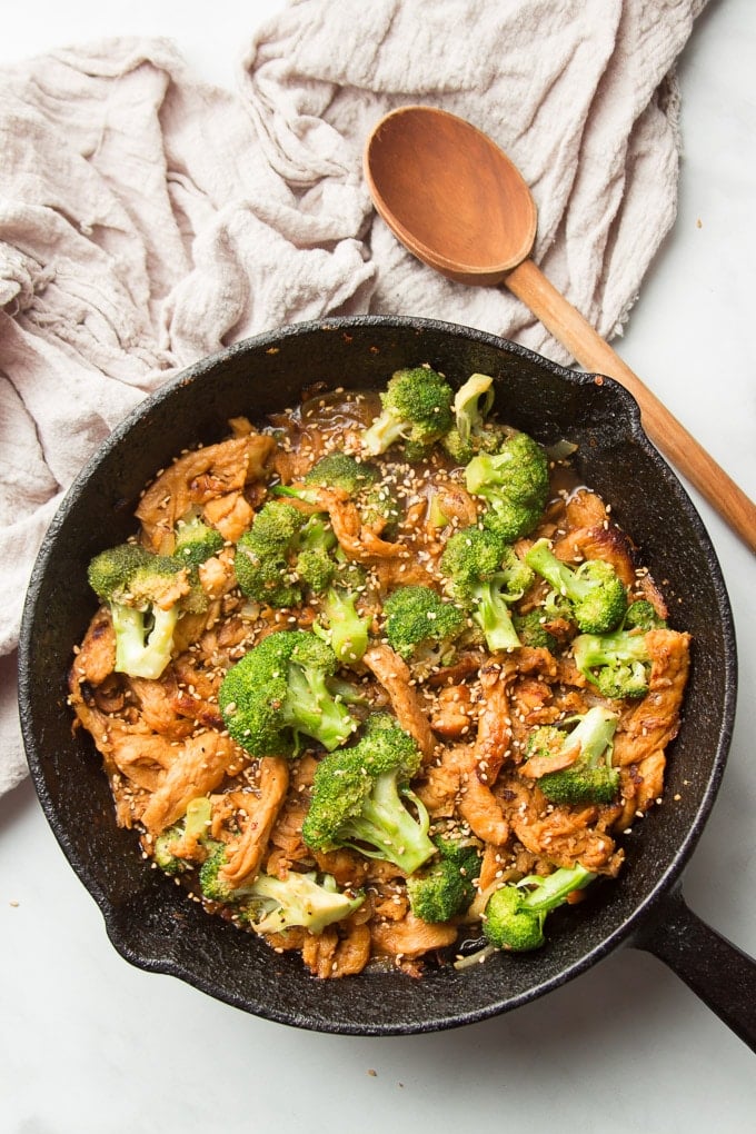 Skillet of Vegan Beef & Broccoli on Marble Surface with Serving Spoon