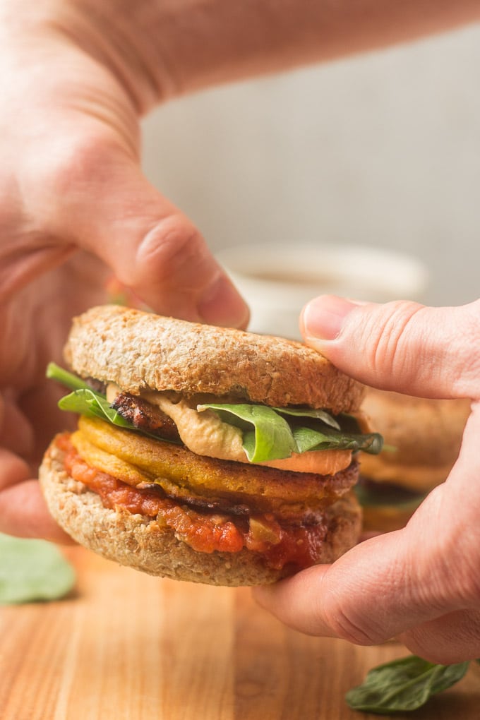Un par de manos sosteniendo un sándwich de desayuno vegano