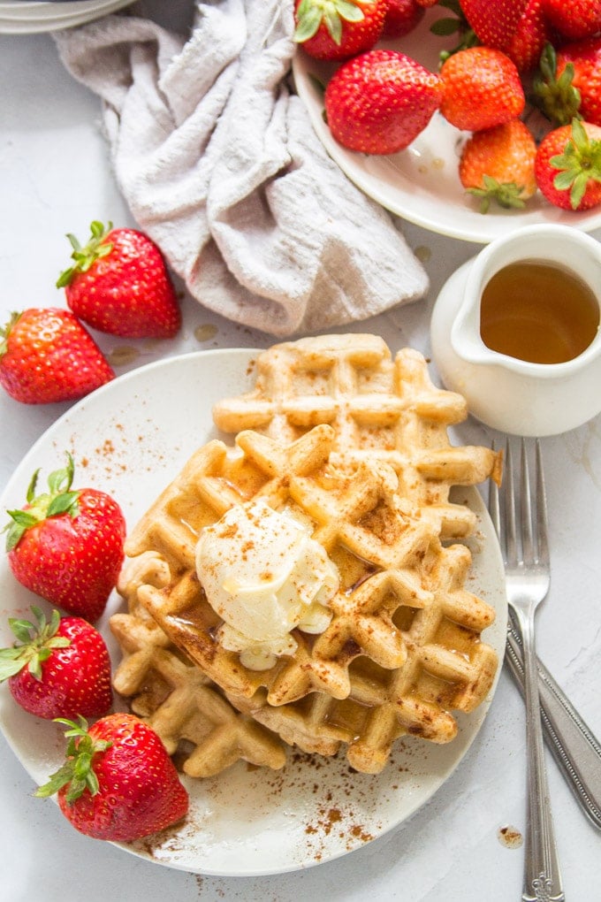 Table Set with a Plate of Vegan Waffles, Bowl of Strawberries, and Container of Maple Syrup
