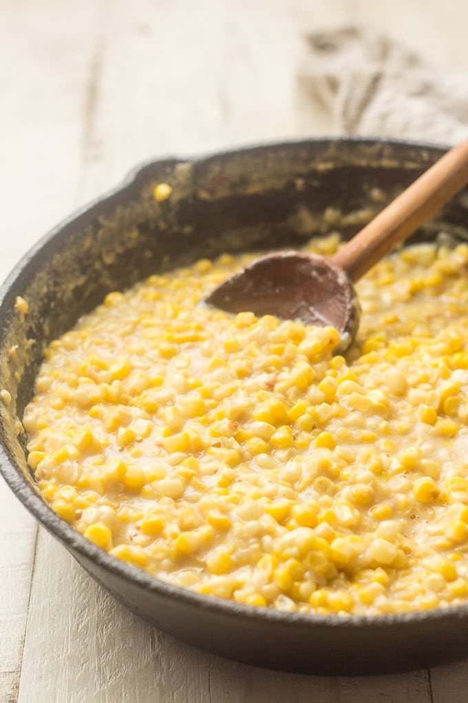 Vegan Creamed Corn in a Cast Iron Skillet with Wooden Spoon