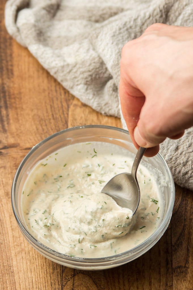 Hand Stirring Tahini Dill Dressing Together in a Bowl