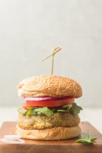Pesto White Bean Burger on a Wooden Surface Against a Grey Background