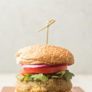 Pesto White Bean Burger on a Wooden Surface Against a Grey Background