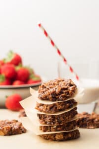 Stack of 5 Vegan No-Bake Cookies with Bowl of Strawberries and Glass of Almond Milk in the Background
