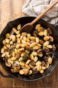 Cast Iron Skillet of Fried Gnocchi and Mushrooms on a Wooden Surface