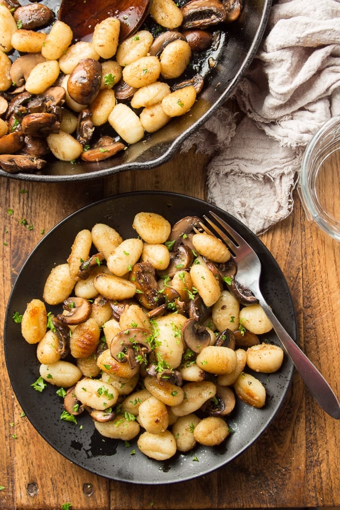 Wooden Table Set with Skillet and Plate of Fried Gnocchi with Mushrooms