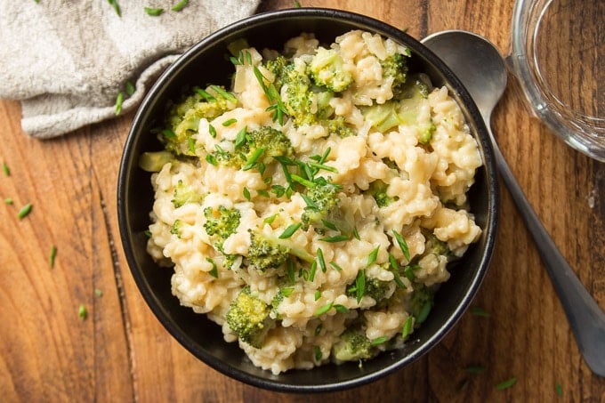 Overhead View of a Bowl of Vegan Broccoli Cheese Risotto on a Wooden Surface