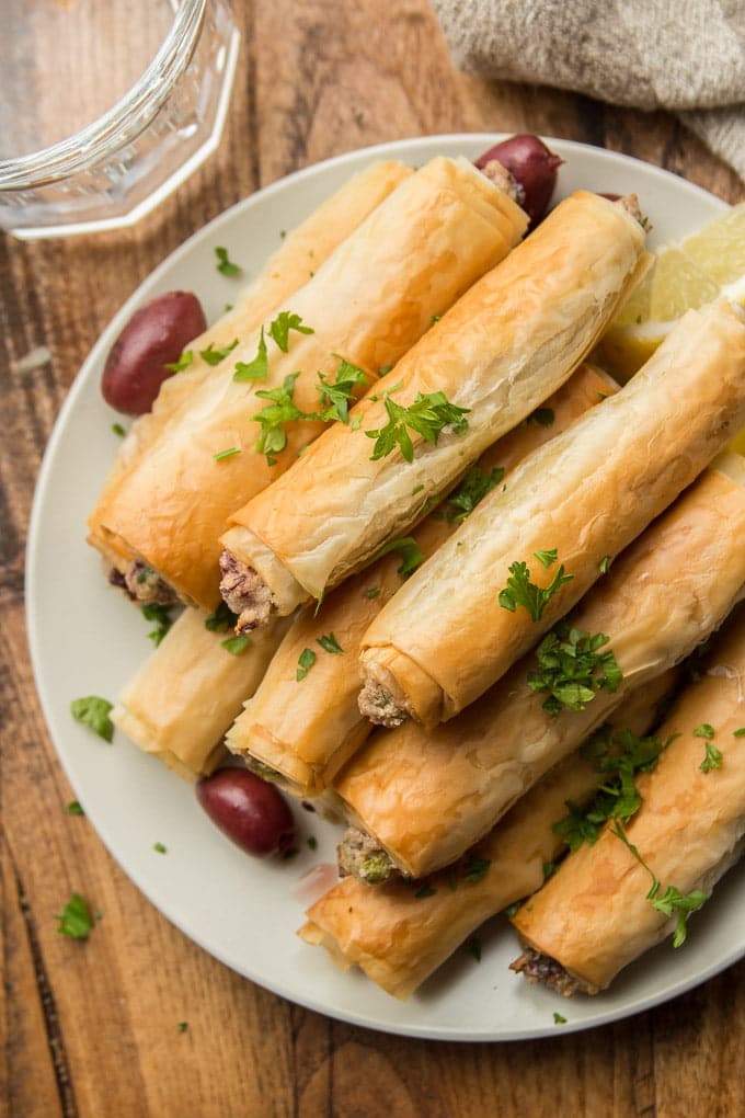 Close Up of Olives and Phyllo Cigars Topped with Parsley on a Plate