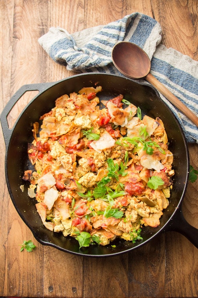 Skillet of Vegan Migas on a Wooden Surface with Napkin and Wooden Spoon