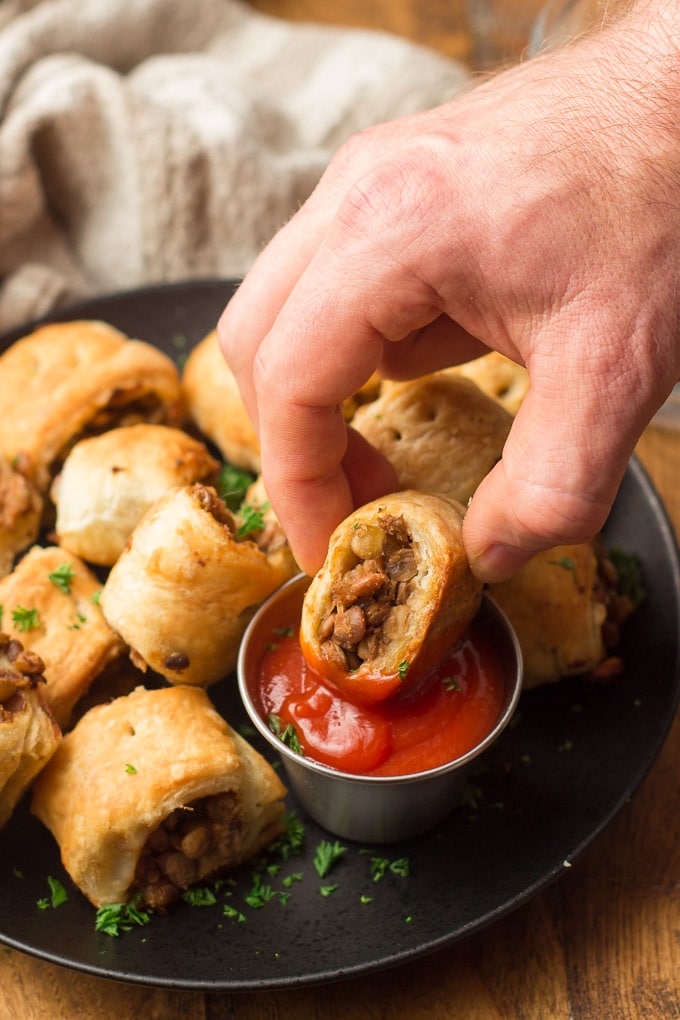 Hand Dipping a Vegan Sausage Roll in a Dish of Ketchup
